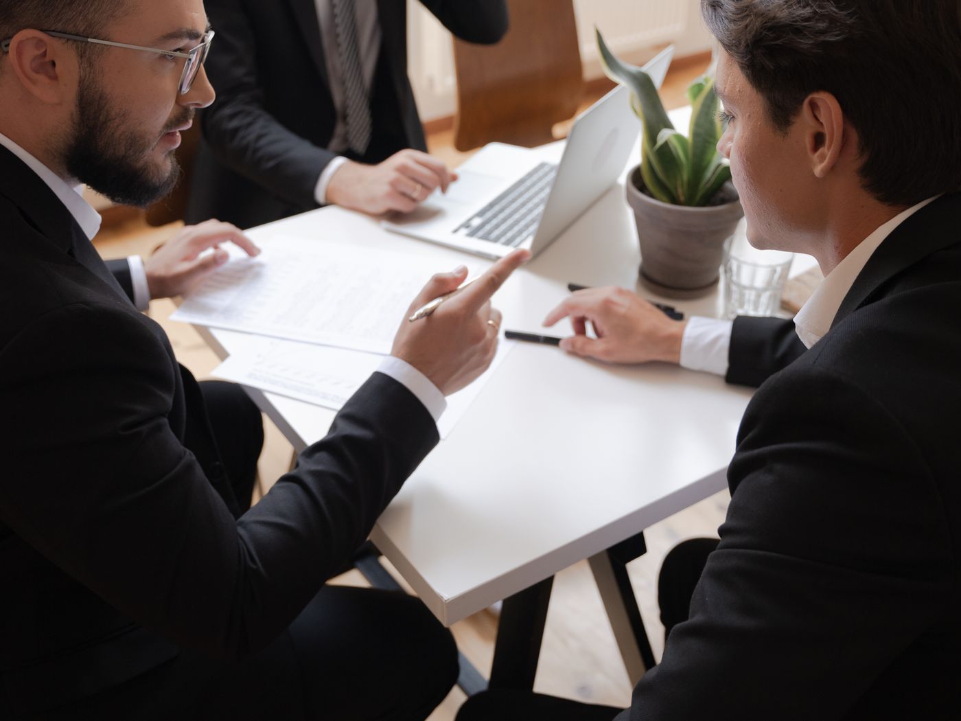 Business leaders in suits reviewing a strategy document together at a meeting table